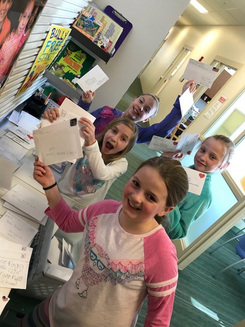 Group of young girls smiling and holding up colorful letters, showcasing unity and teamwork.