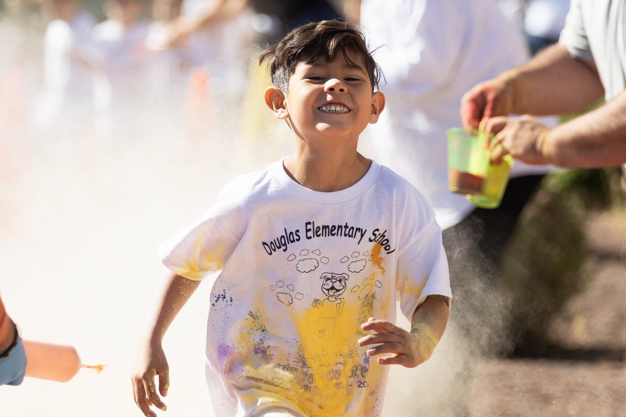 A young boy smiles as he participates in the school Color Run fundraiser.