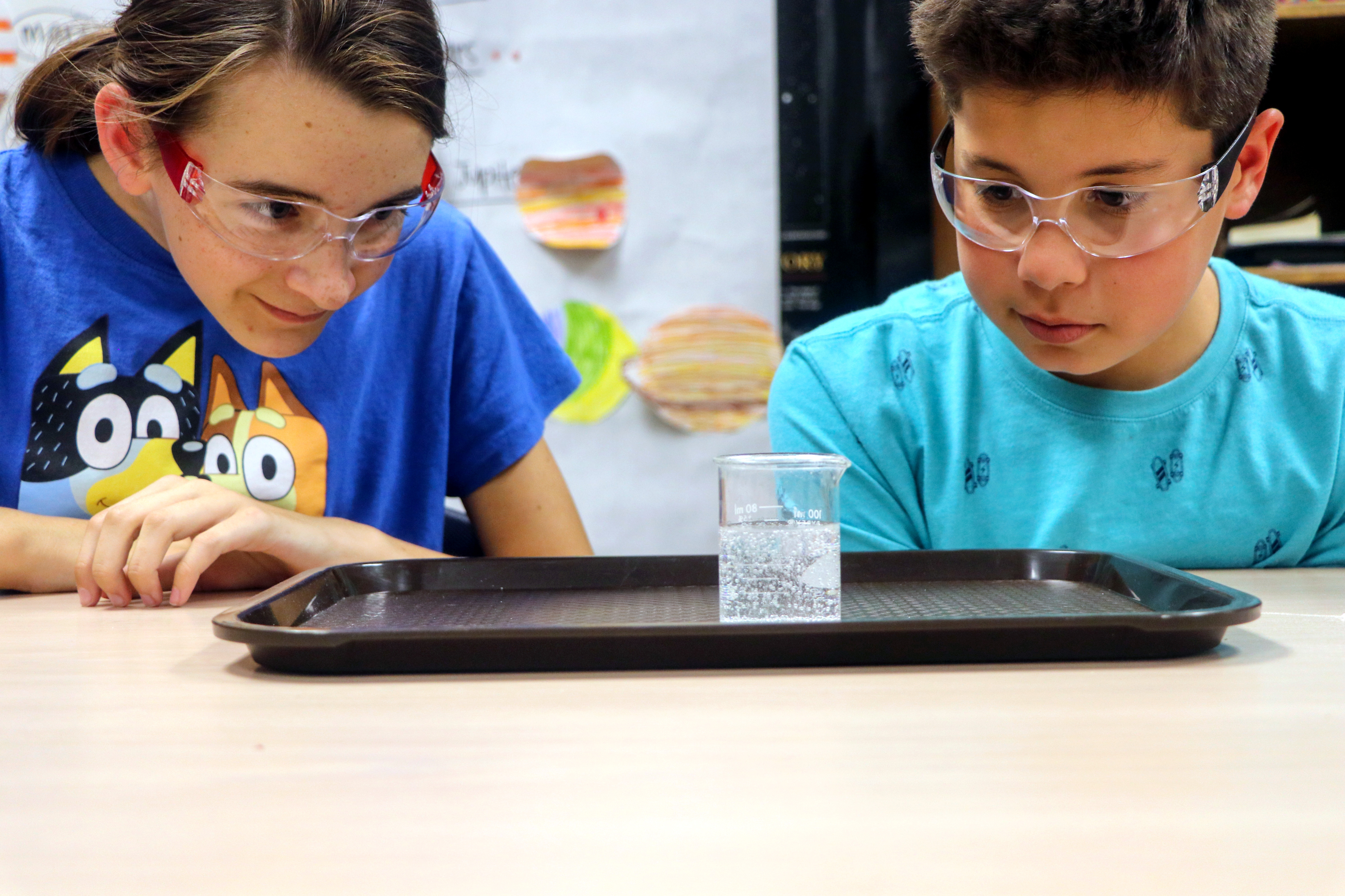two students observing a beaker of liquid.