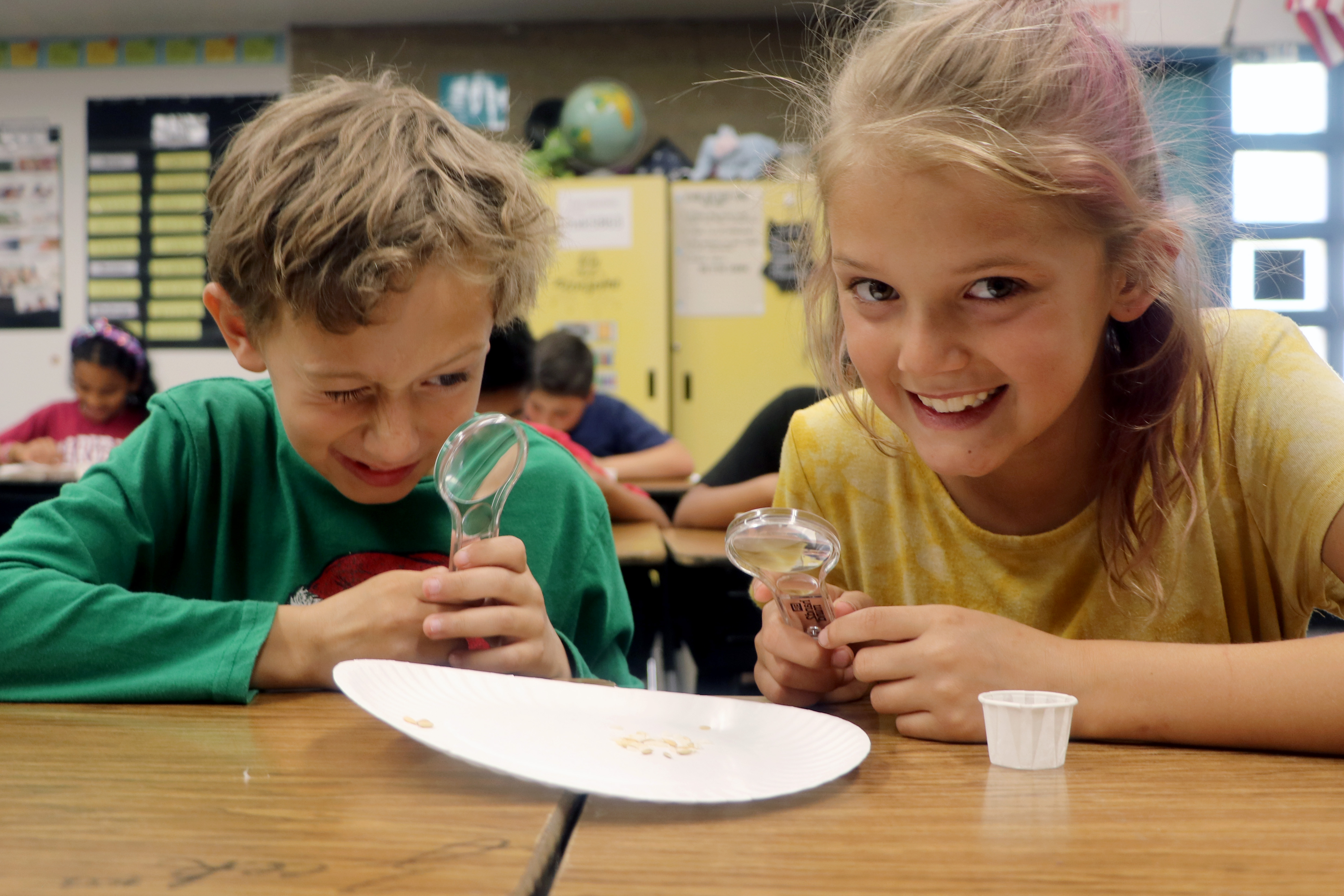 two students observing with magnifying glasses