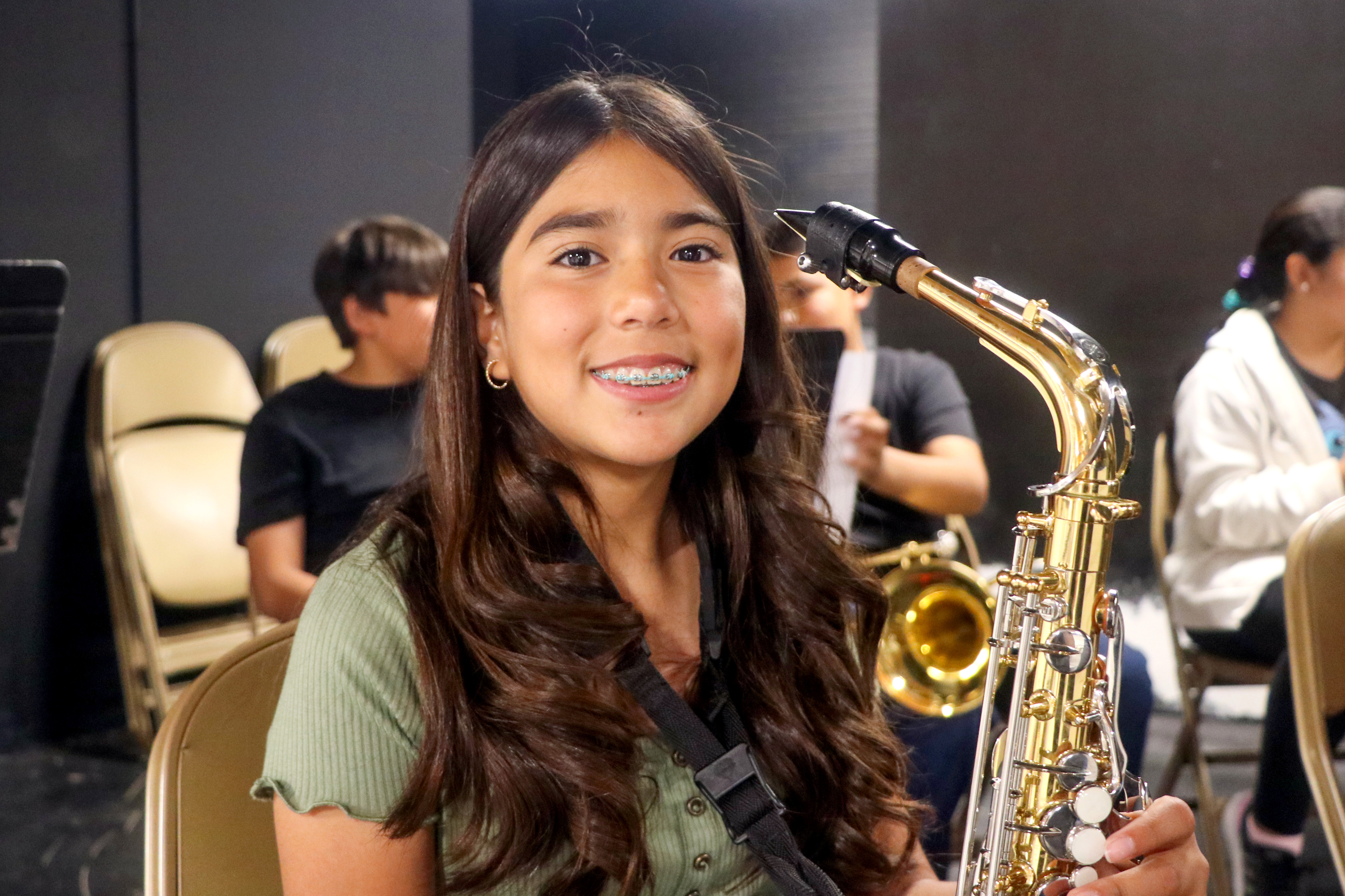 Girl smiles while holding her saxophone.