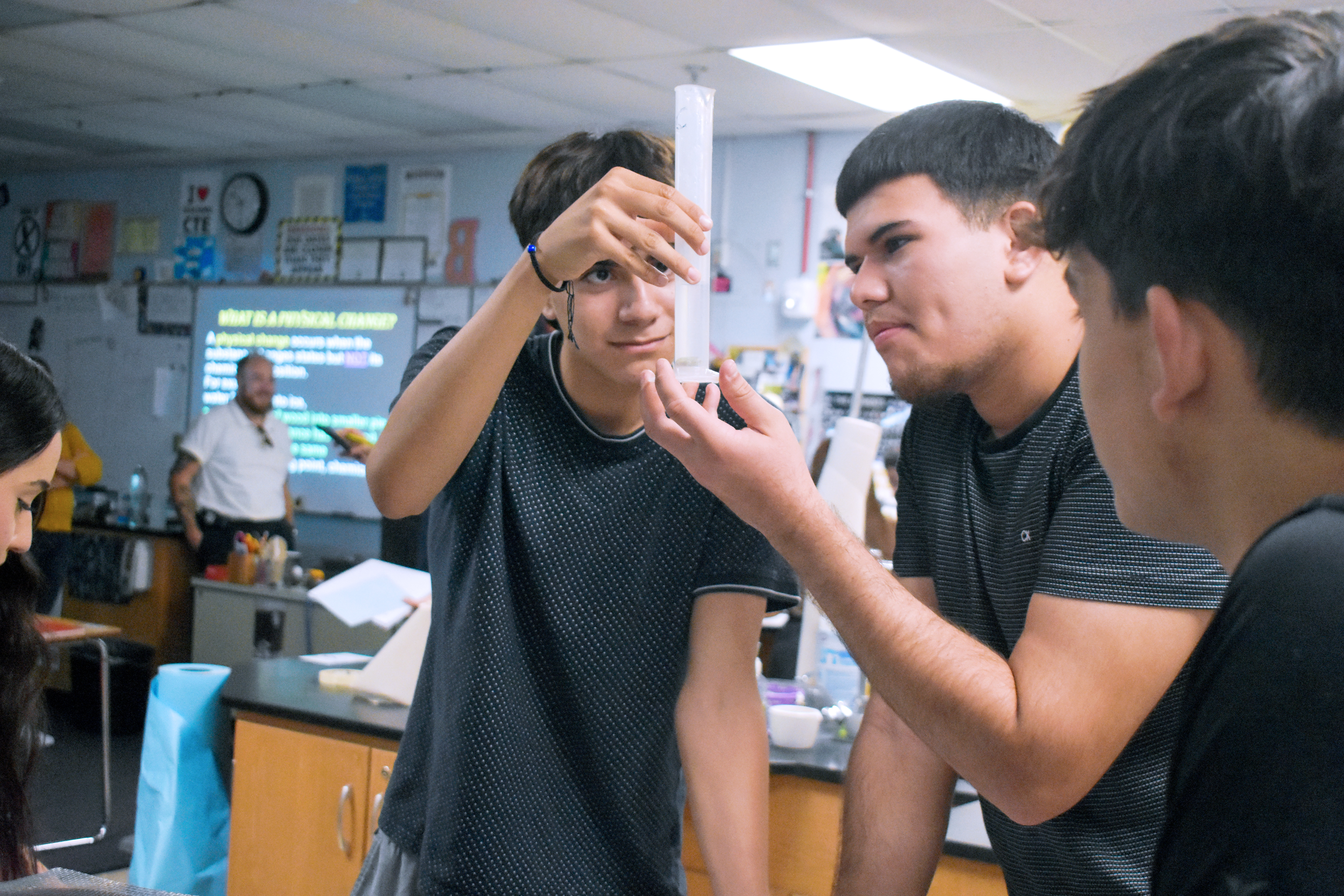 High school students conducting a science experiment in the classroom, focusing intently on a test tube.