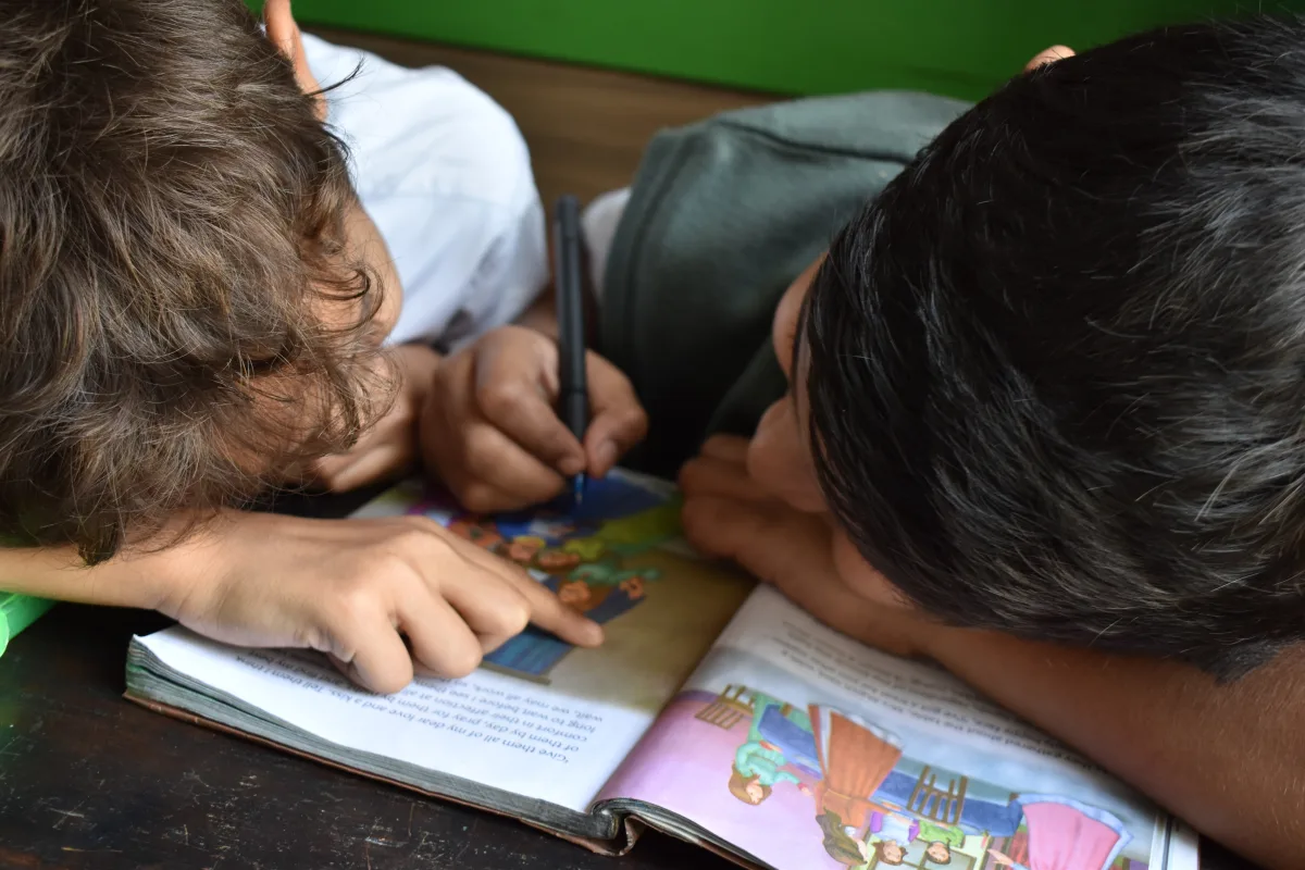 A couple of kids writing in a book