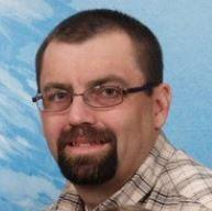 man with dark brown hair and beard wearing glasses