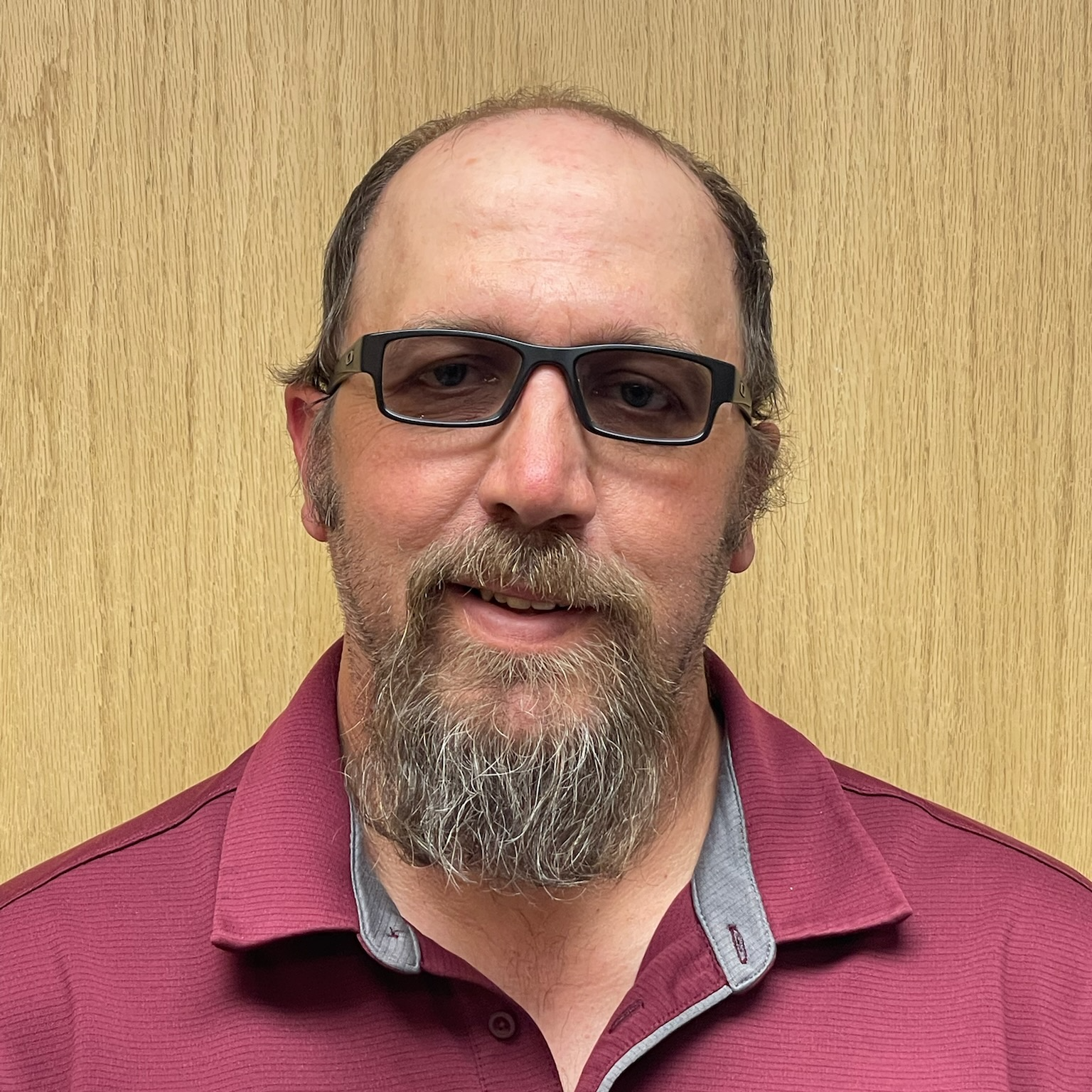 man with glasses and beard wearing maroon shirt