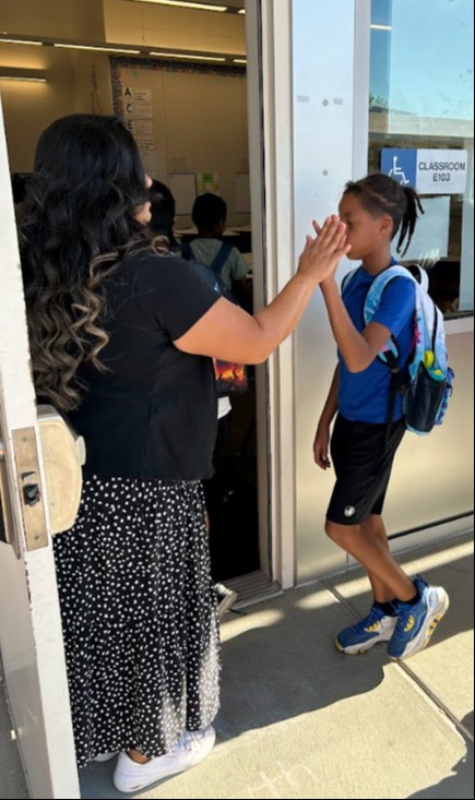 Teachers welcome students with a choice as they enter the classroom. / Los profesores reciben a los alumnos con una elección al entrar en clase.