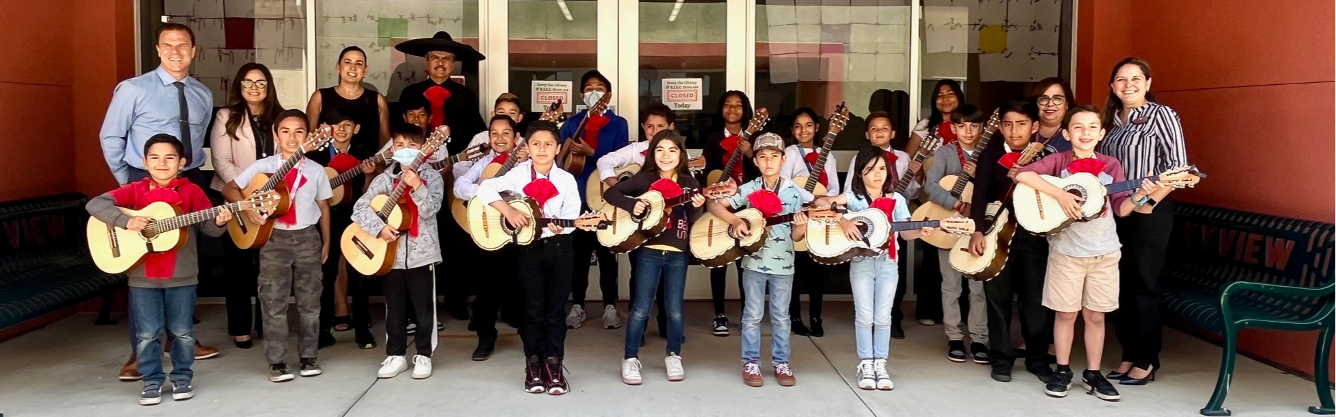 picture with students holding guitars including district superintendent and asst superintendent
