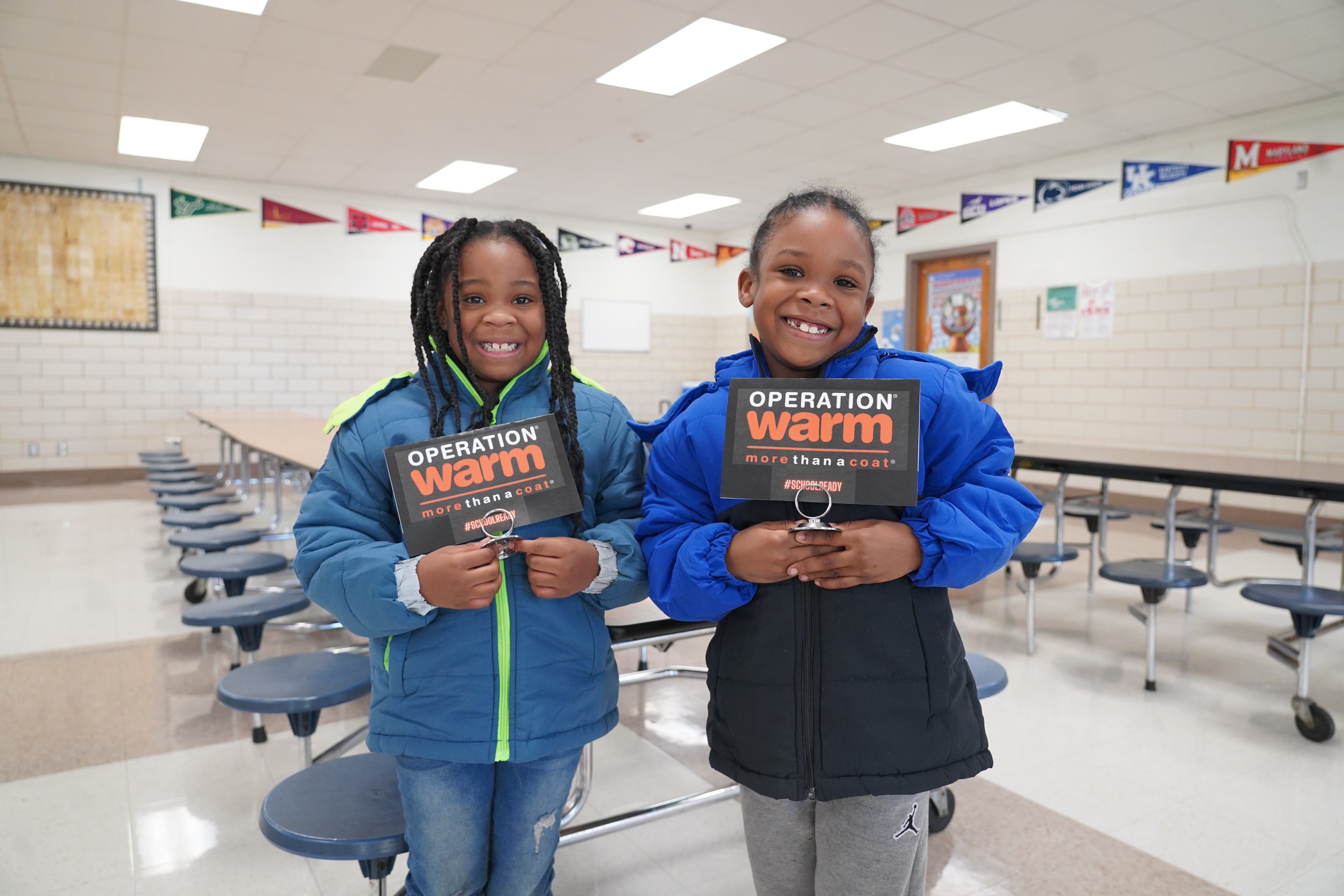 Two Hommel Students Holding "Operation Warm" signs.