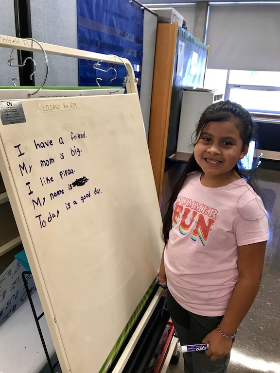 Image of student smiling in front of her work.