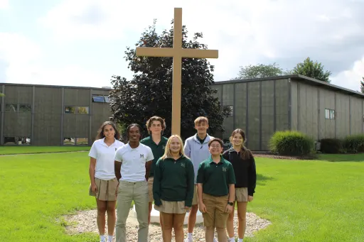 Group of People standing infront of a Cross