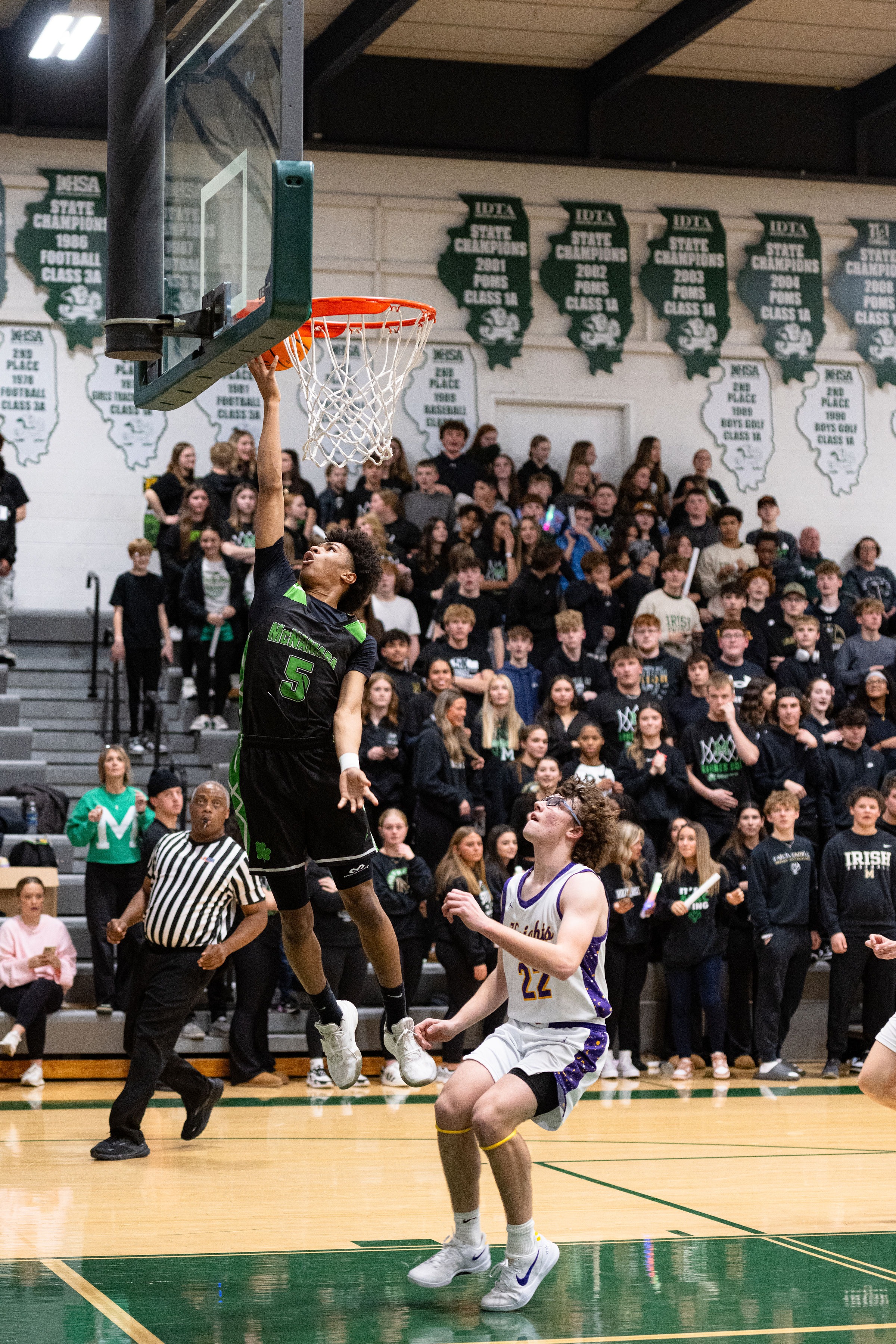 A picture of student basketball athlete holding a basketball ball with a crowd behind him