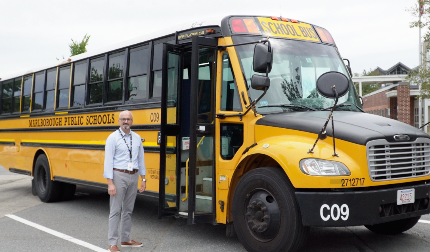 Superintendent Jason DeFalco stands next to a yellow school bus.