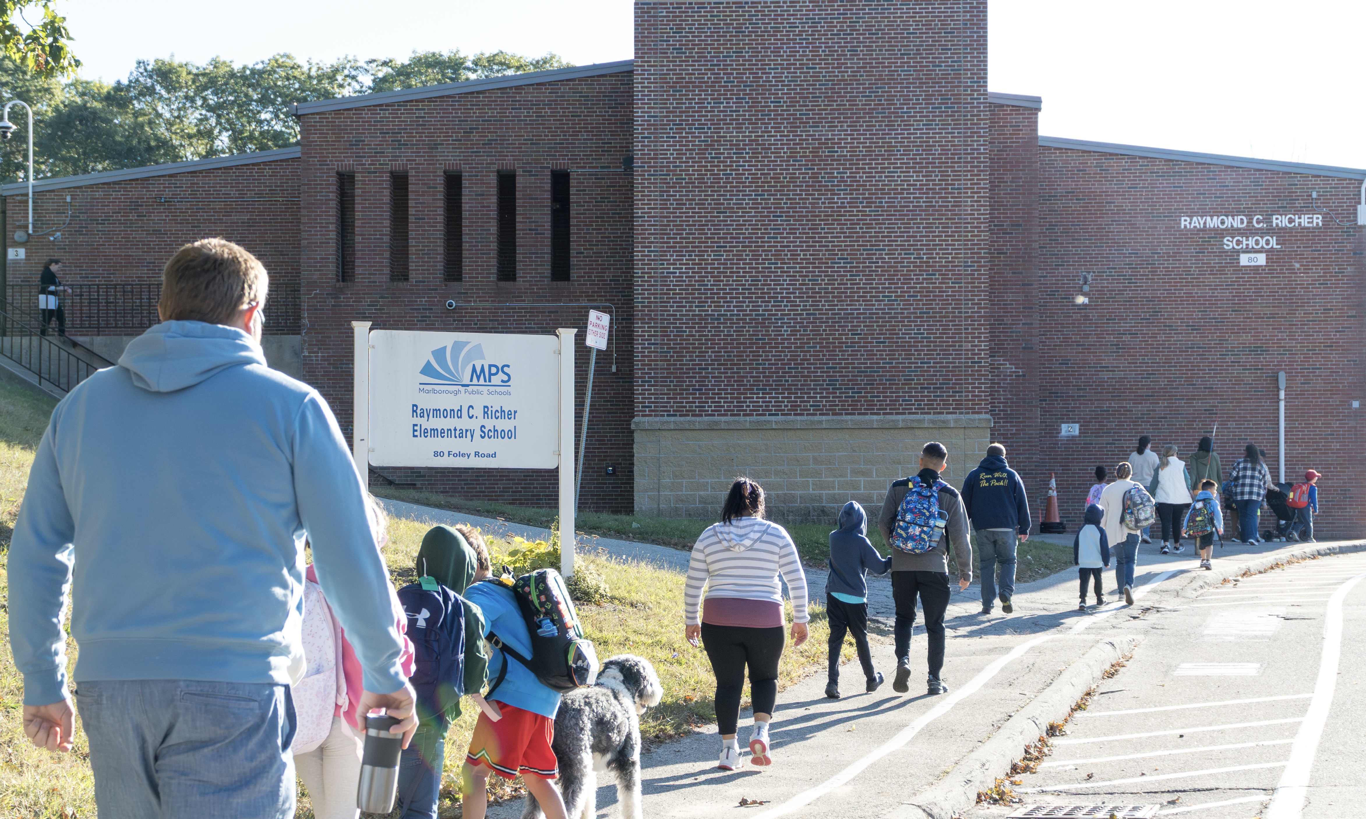 A group of students and parents walk outside toward the Richer School.