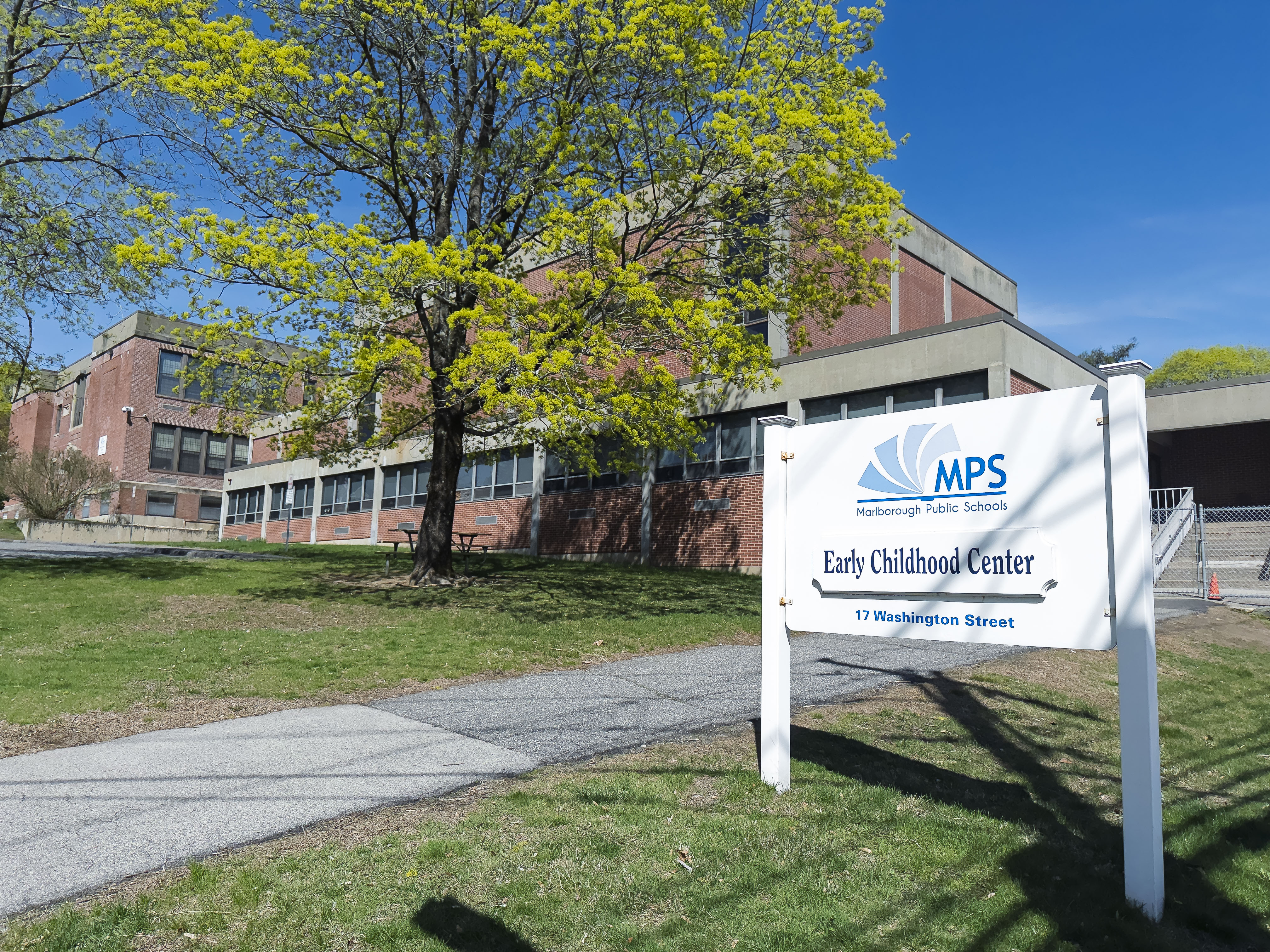 A white signboard reads "MPS Early Childhood Center" in front of a building. The area is surrounded by grass and trees.