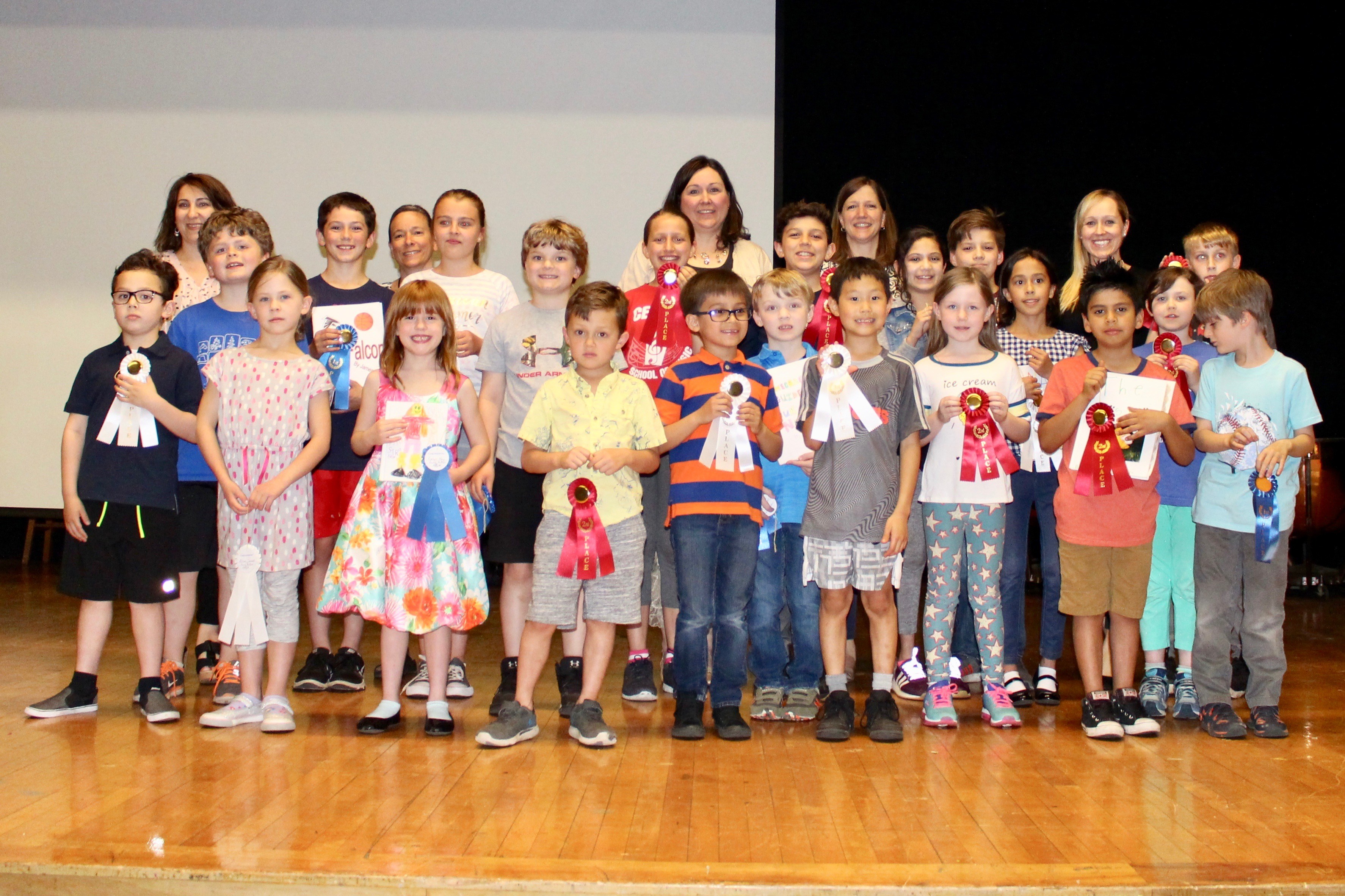 A diverse group of children and adults proudly displaying their awards at a ceremony.