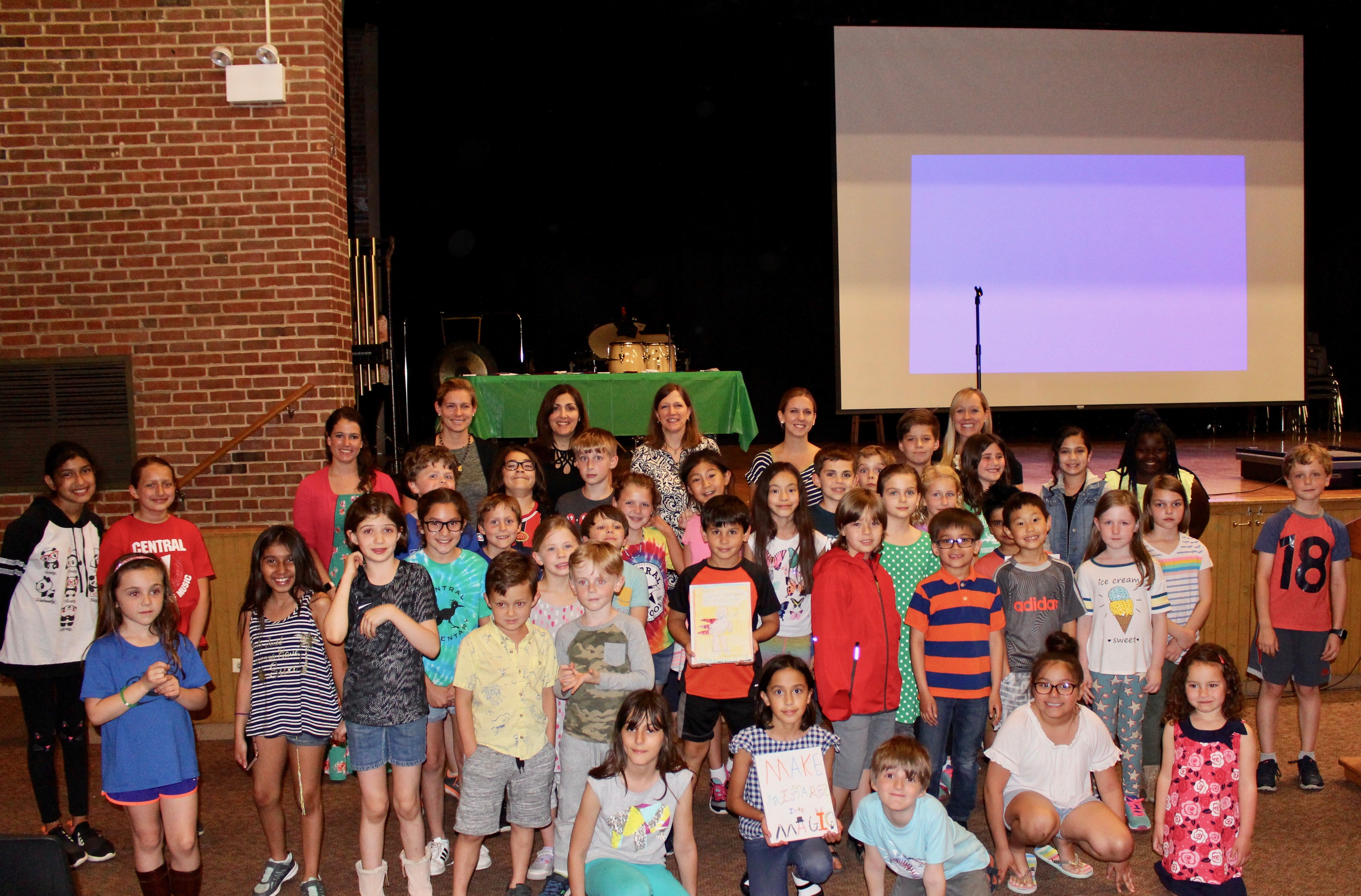 A diverse group of children and adults smiling and posing together for a group photo.