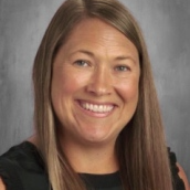 A woman with long straight brown hair wearing a black and white shirt.