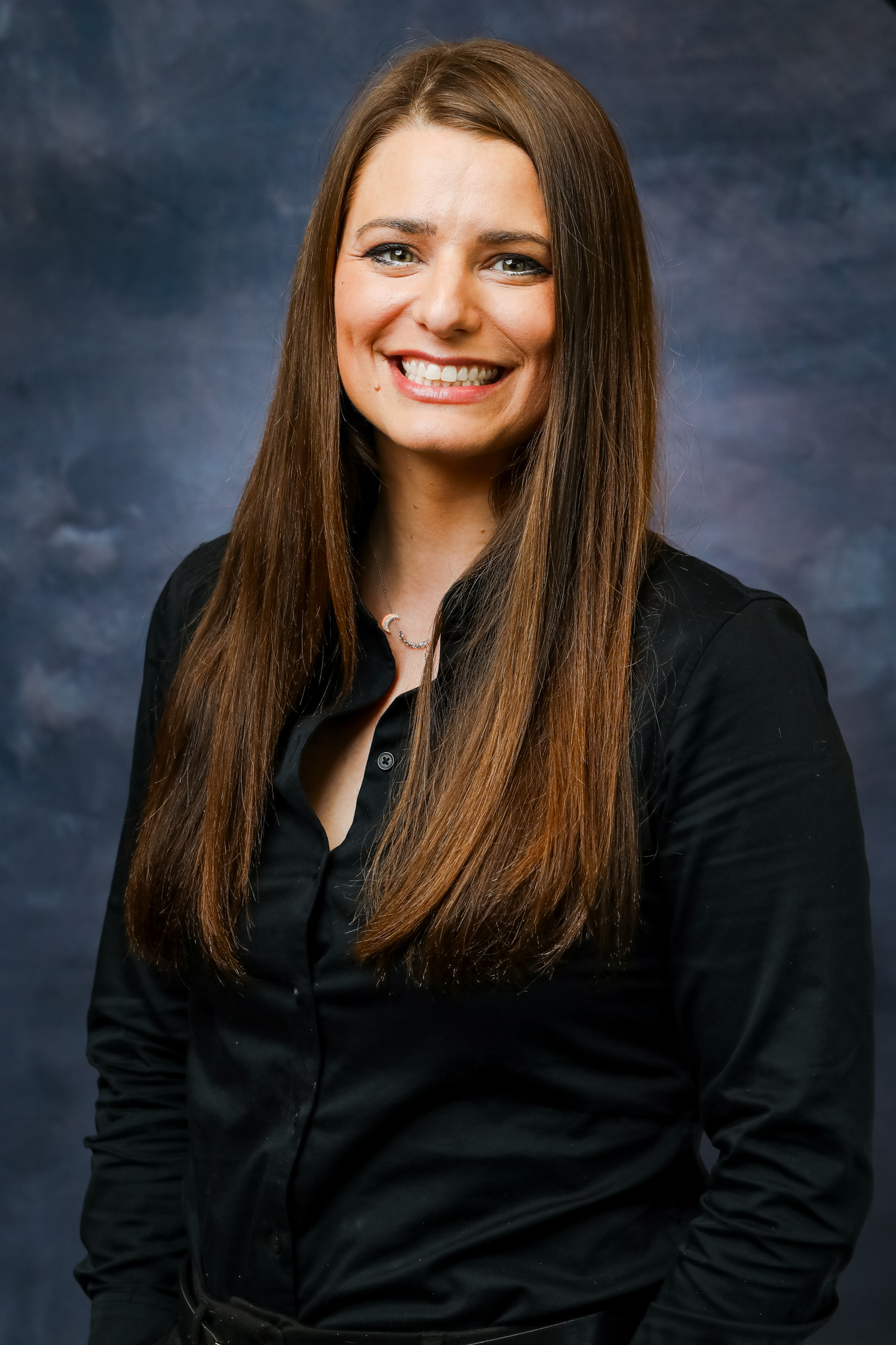 A woman with straight brown hair wearing a black button down