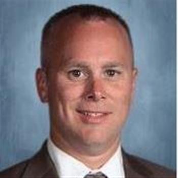 A professional man wearing a suit and tie with a pleasant expression on his face.