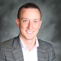 A man in a suit and tie smiling for a photo.