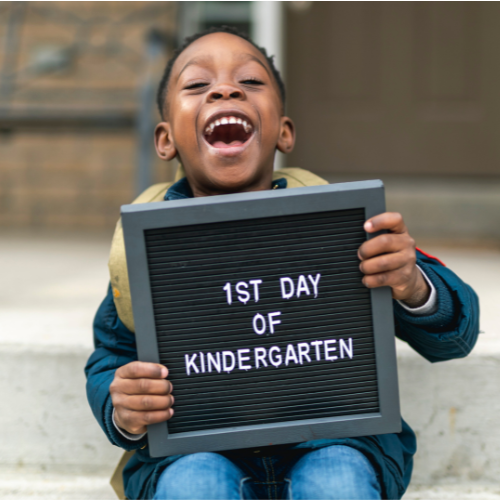 Student holding sign that says "first day of kindergarten"