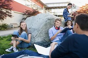 students talking to each other outside around an on campus spirit rock
