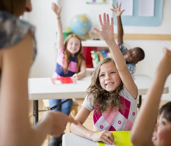 students raising hands in a classroom