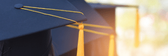 A black graduation cap with a flat square top and a tassel hanging off the corner. The cap is in focus and fills the frame.