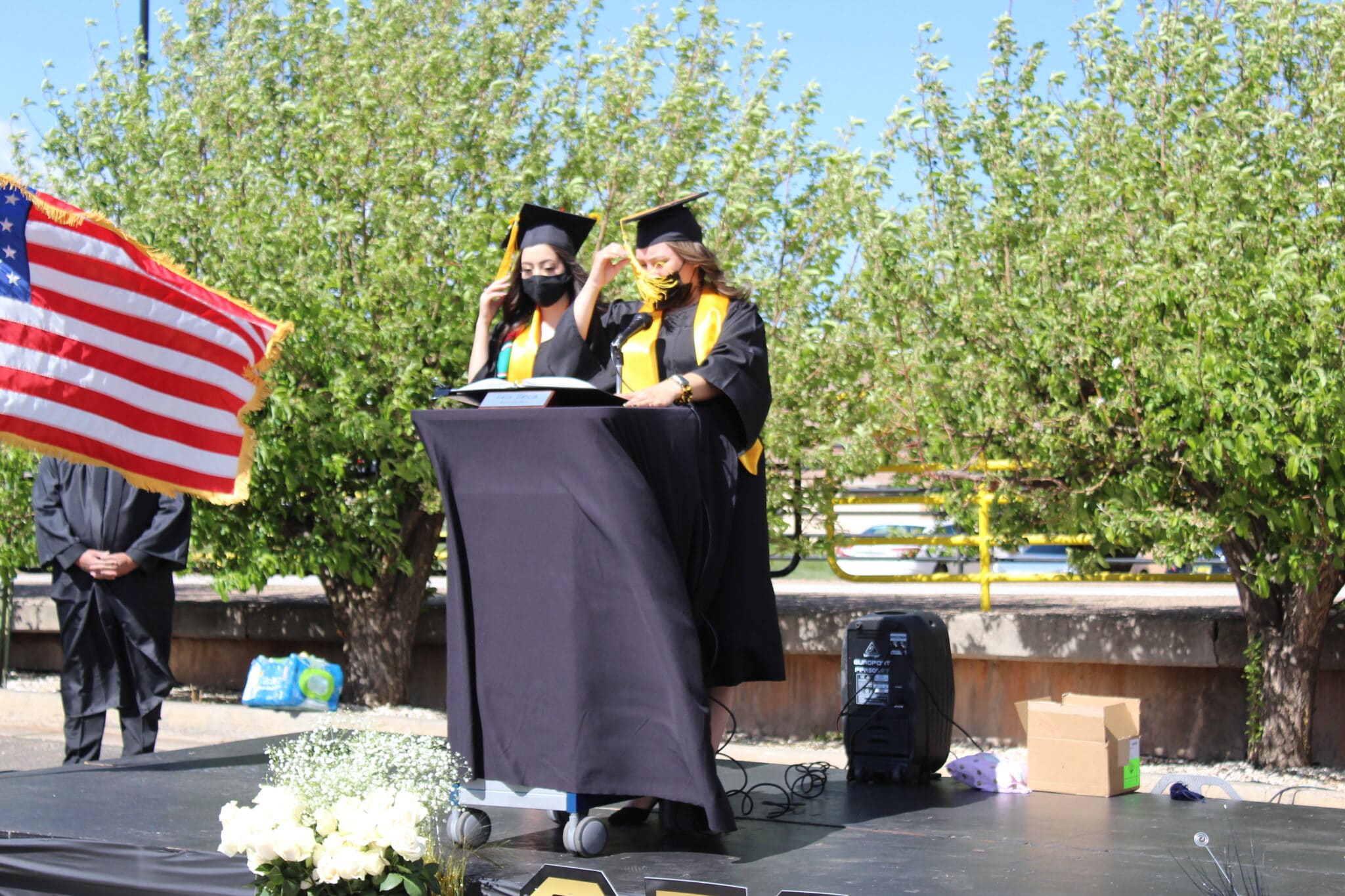 Two students in graduation gowns and caps on stage