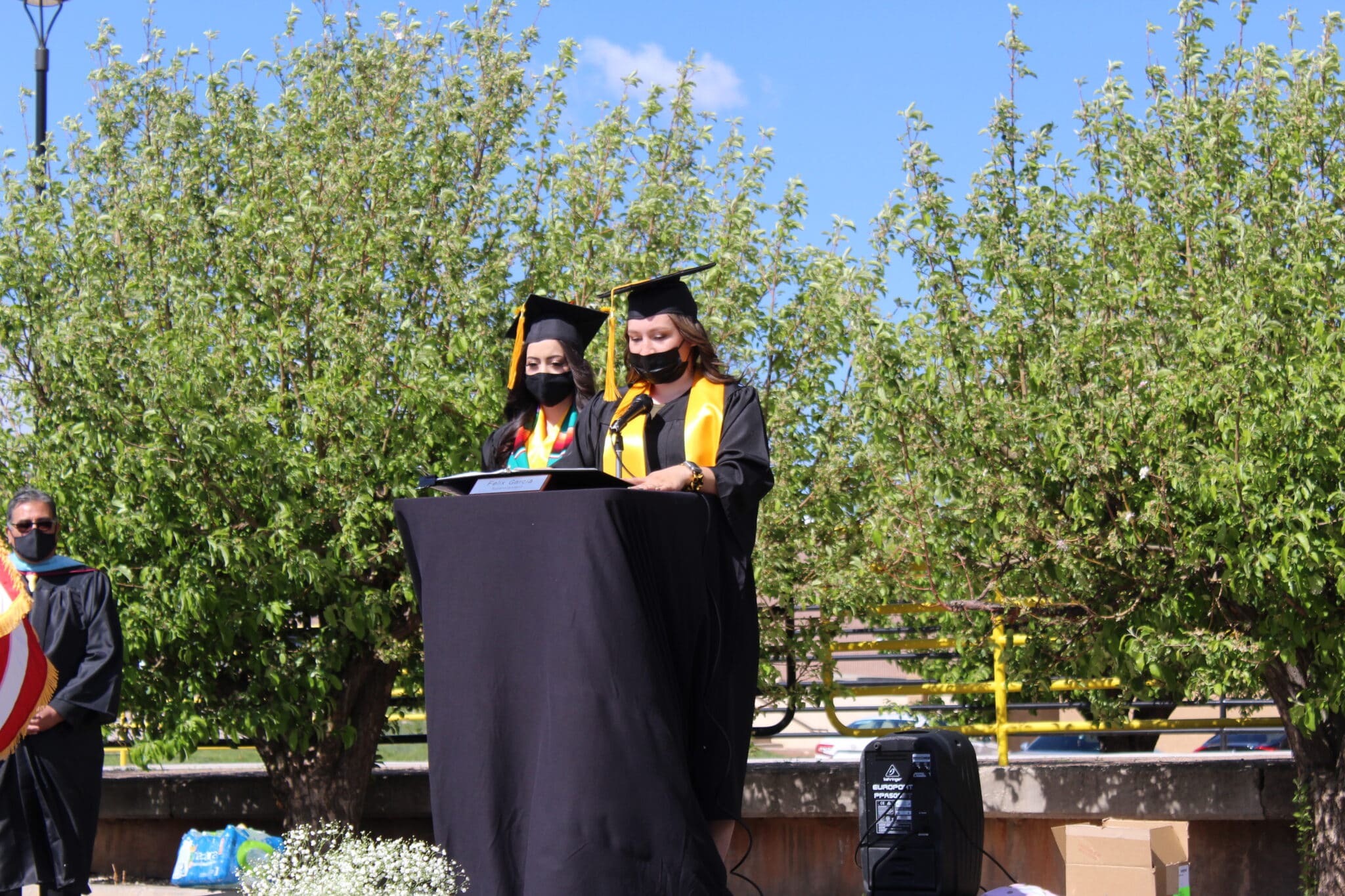 Two students in graduation gowns and caps on stage