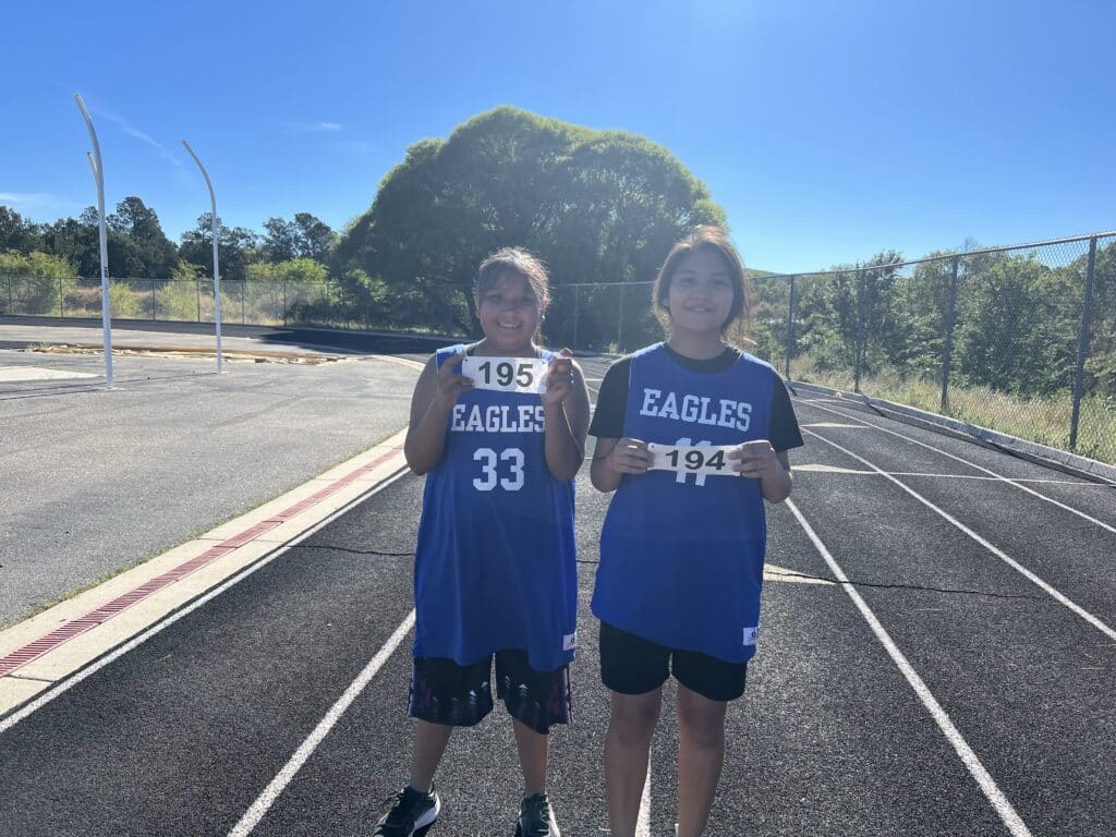 Students wearing blue jerseys on a track field.