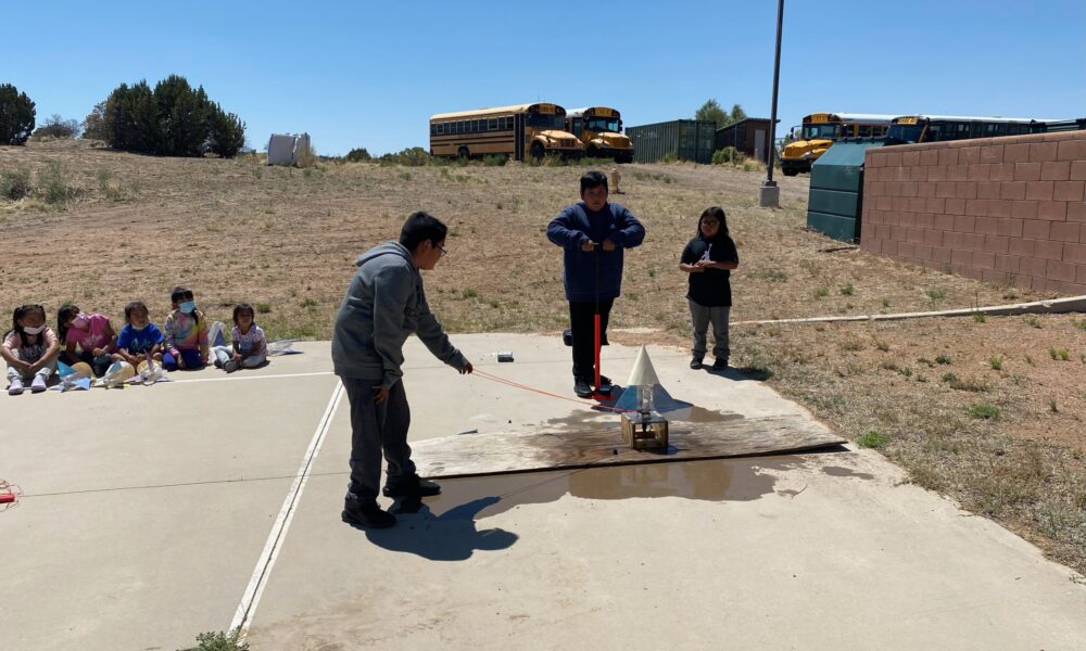 Students experimenting with a rocket outdoors.