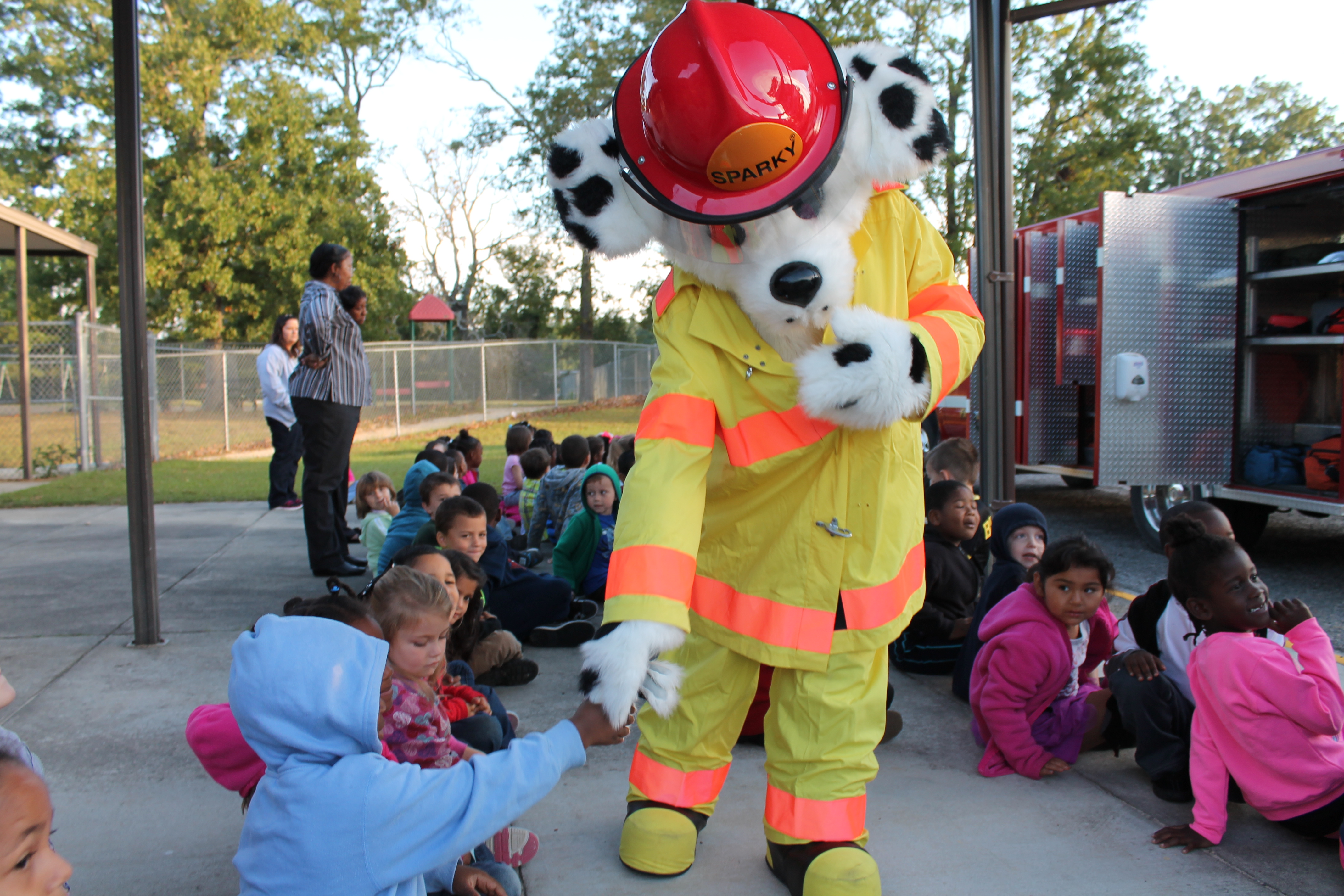 Sparky the Fire Dog shaking hands with students