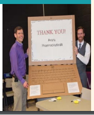 Two men holding a cardboard computer: Thank you