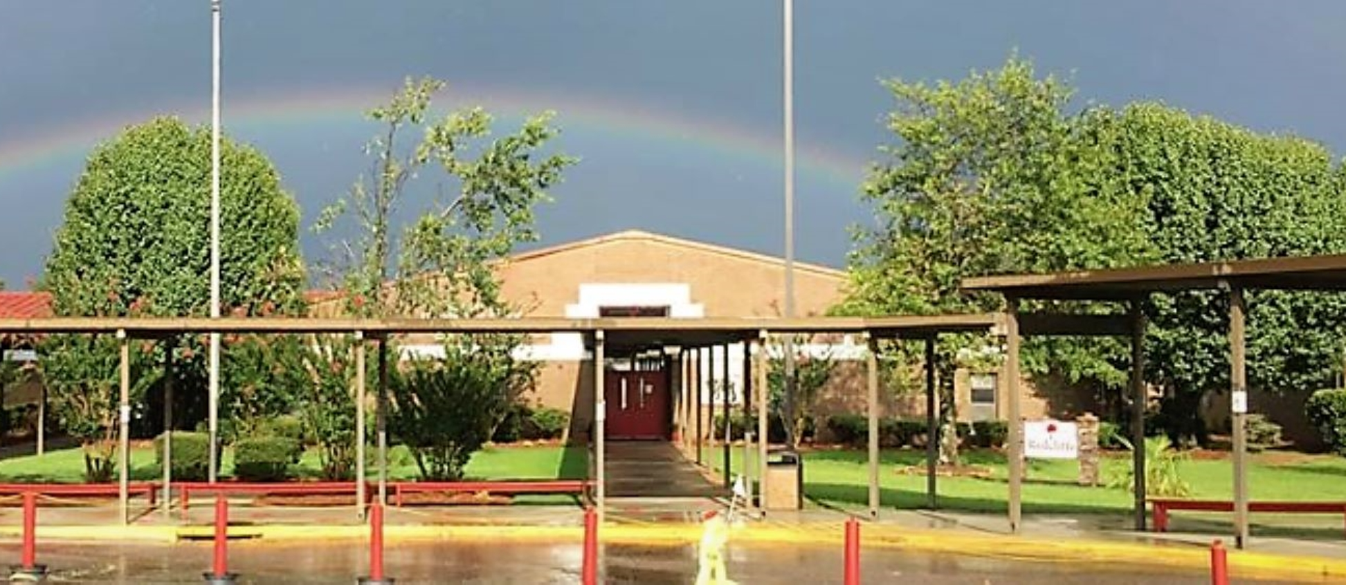 School building in front of rainbow.