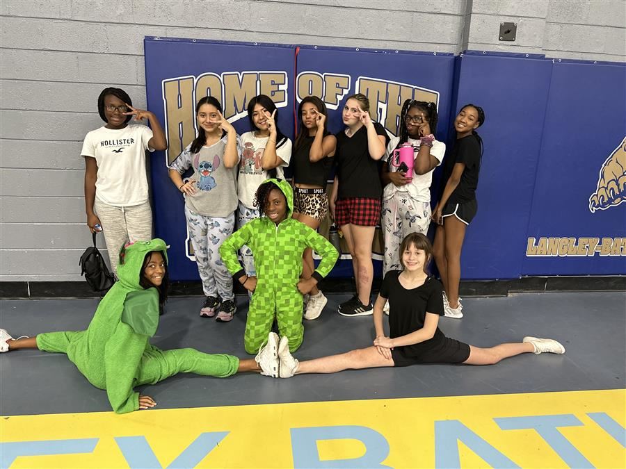 This is an image of mutiple members of the cheer team posing. This included two girls in the front doing the splits and the ladies in the back doing the fierce sign. 