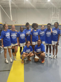 This is an image of the girls basketball team posing and looking at the camera on a court. 