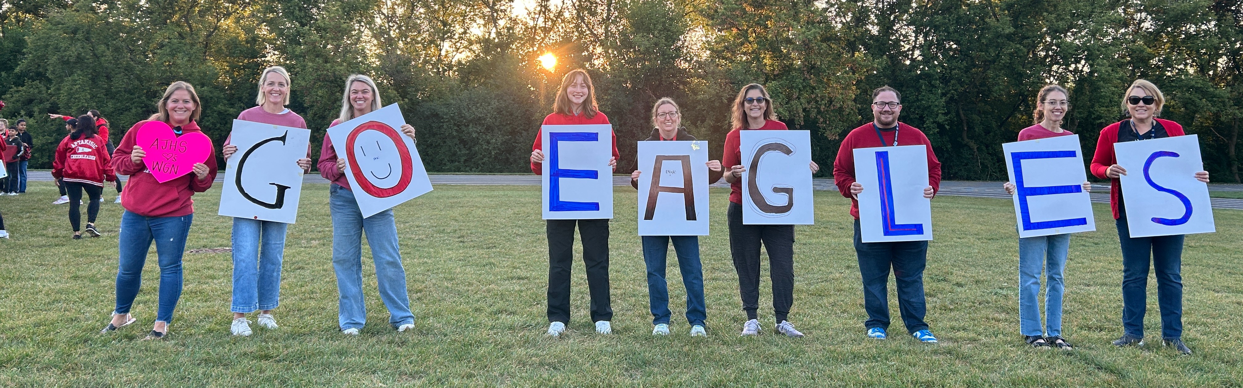 staff holding a sign that spells AJHS