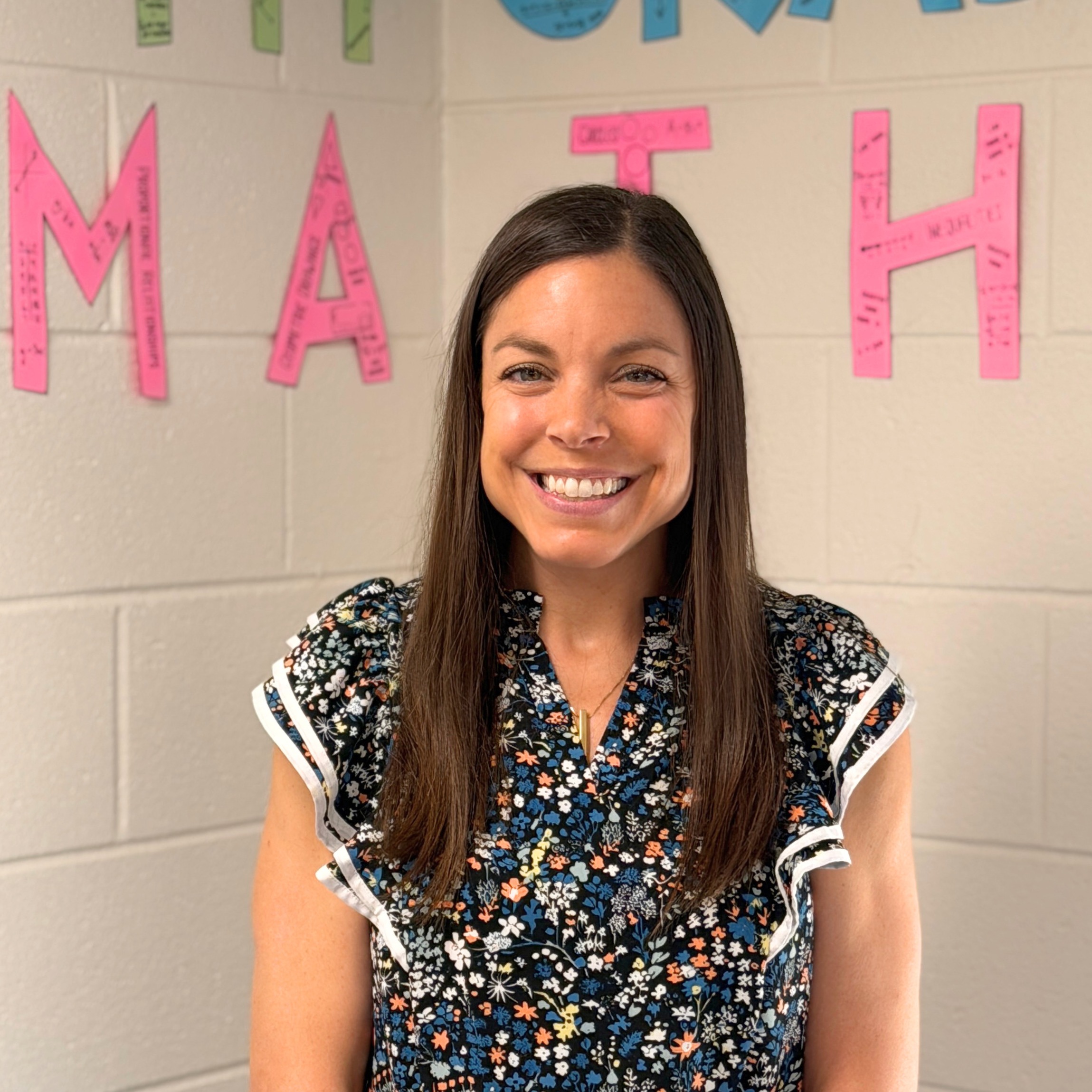 Mrs. Guliano standing in front of a wall that says 7th-grade math.