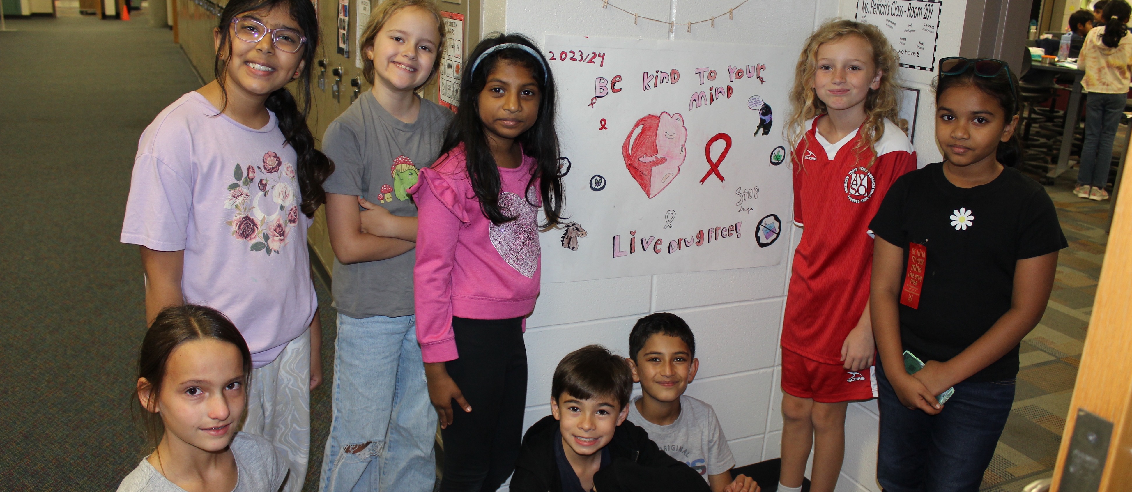 A group of students pose in front of their Red Ribbon Week poster