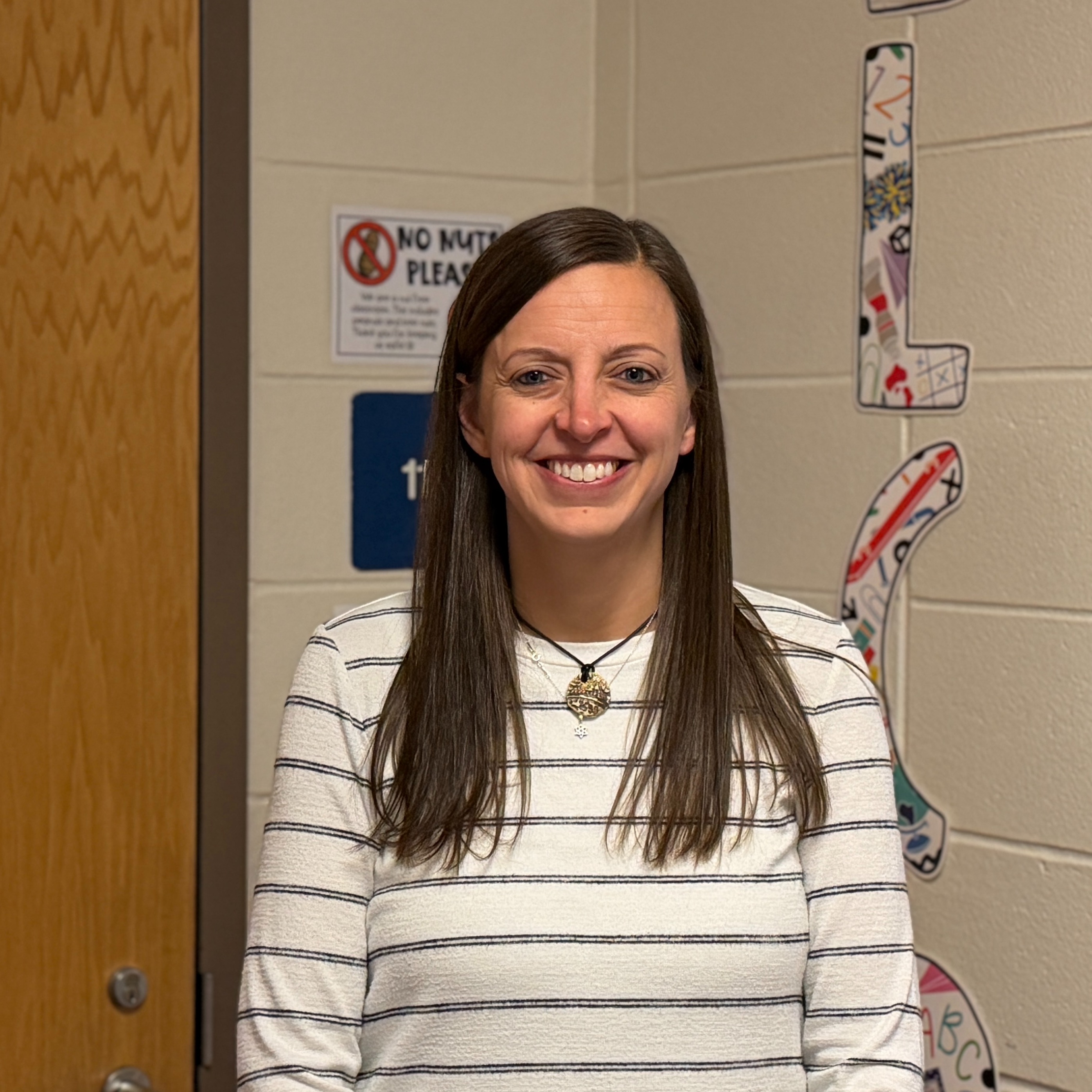 Headshot of Mrs. Salus standing outside of her classroom door.
