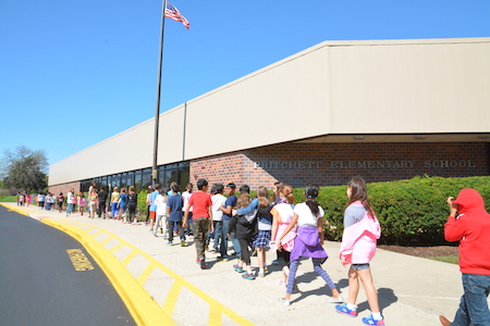 Pritchett Elementary building with students walking on the sidewalk