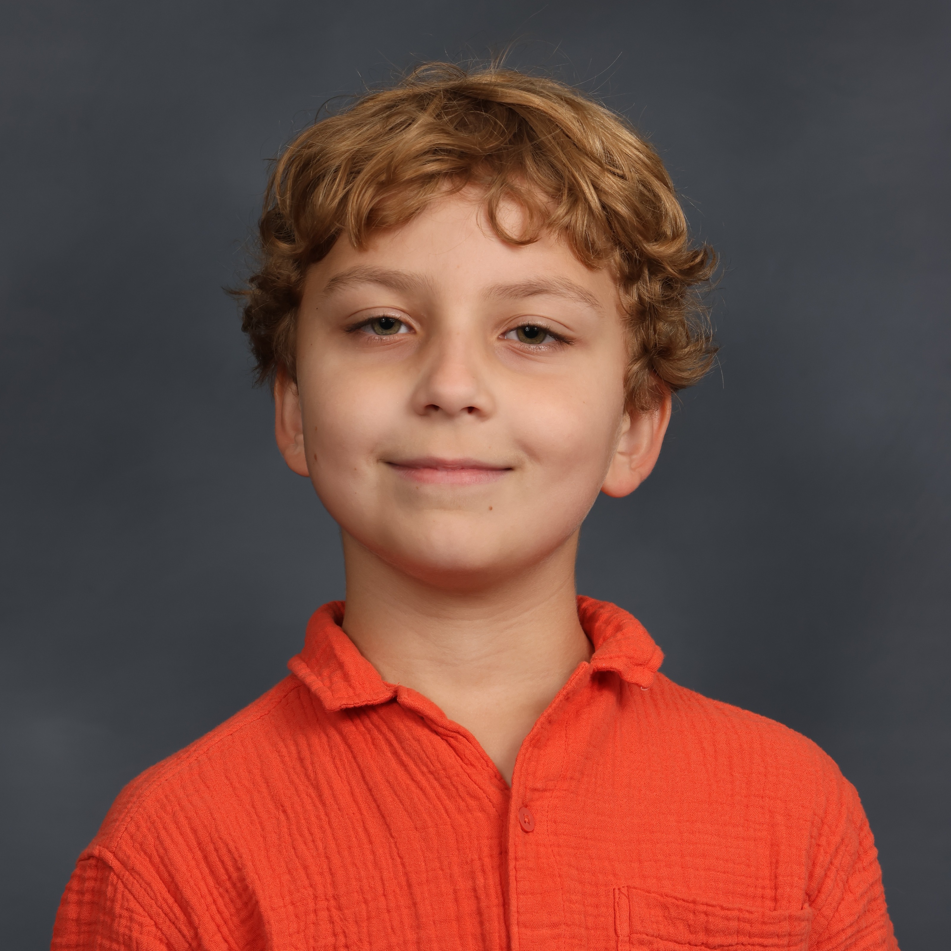Little boy headshot in an orange shirt and blonde hair.