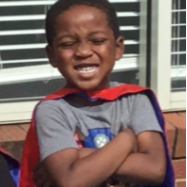 Little boy grinning with crossed arms and superhero cape