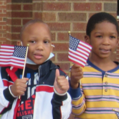 Two boys smile while holding US flags