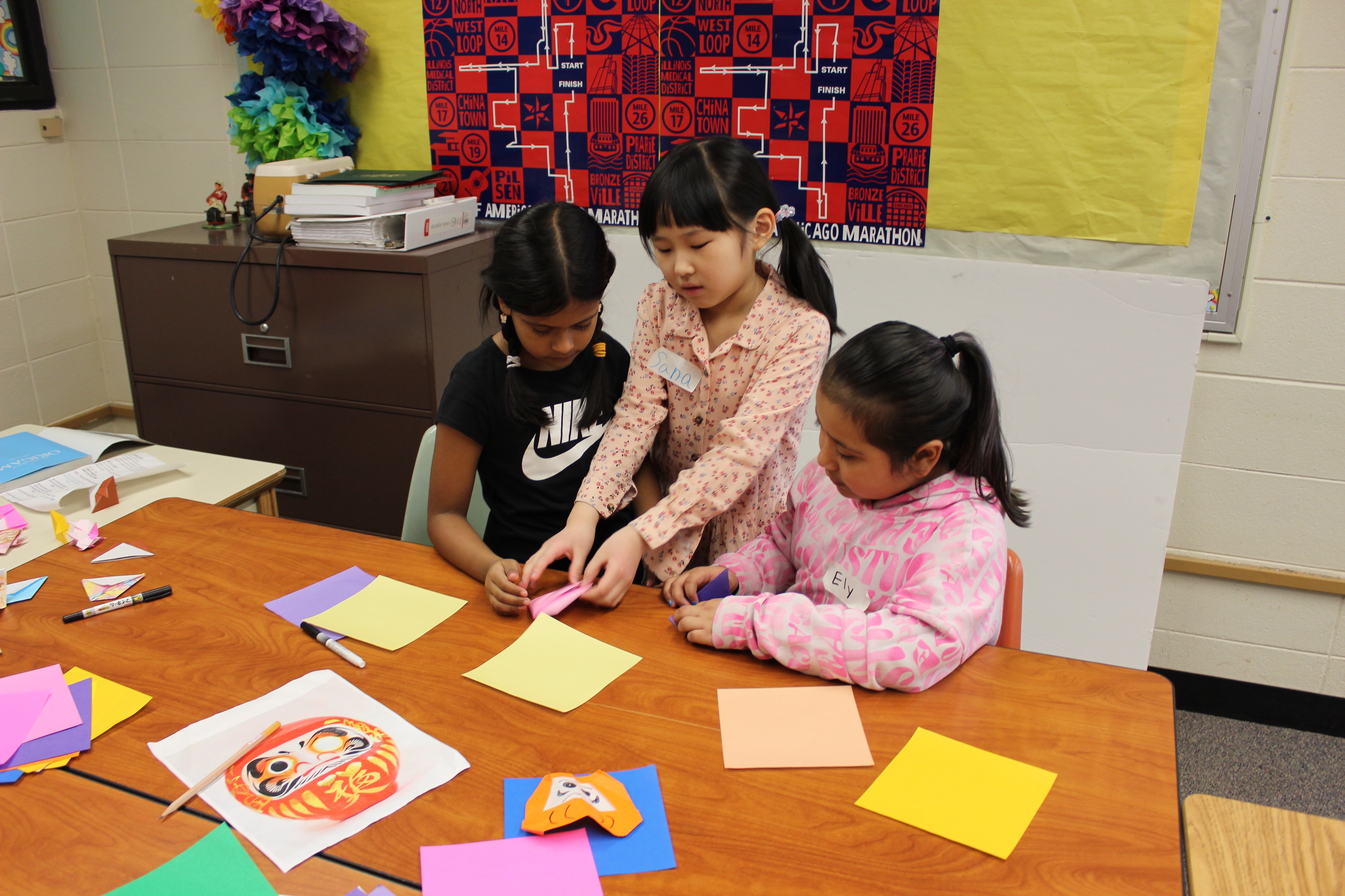 Three third graders work together on oragami