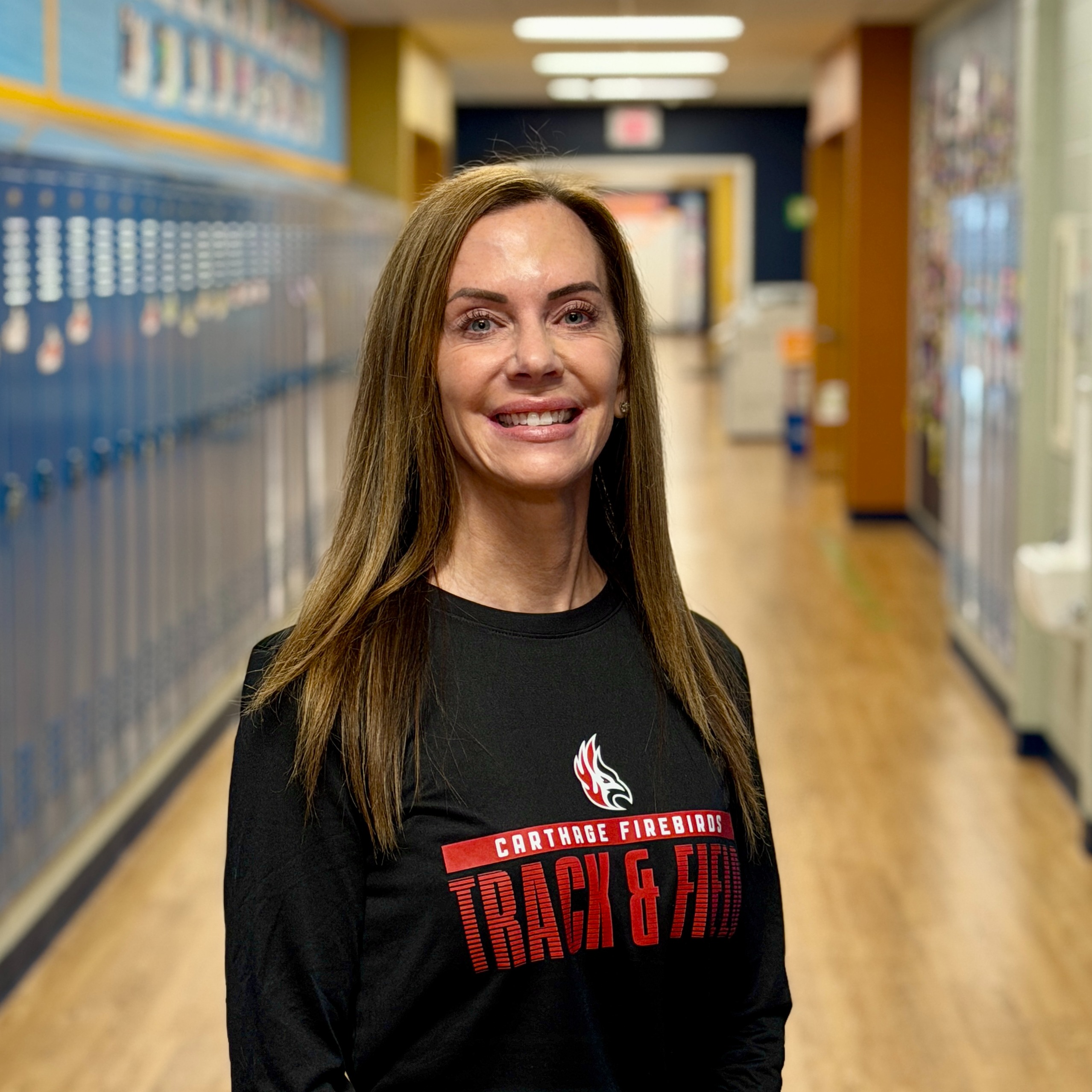 Headshot of Mrs. Schenk standing in the hallway with lockers around.
