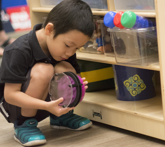 kid sitting in the floor looking at a toy 