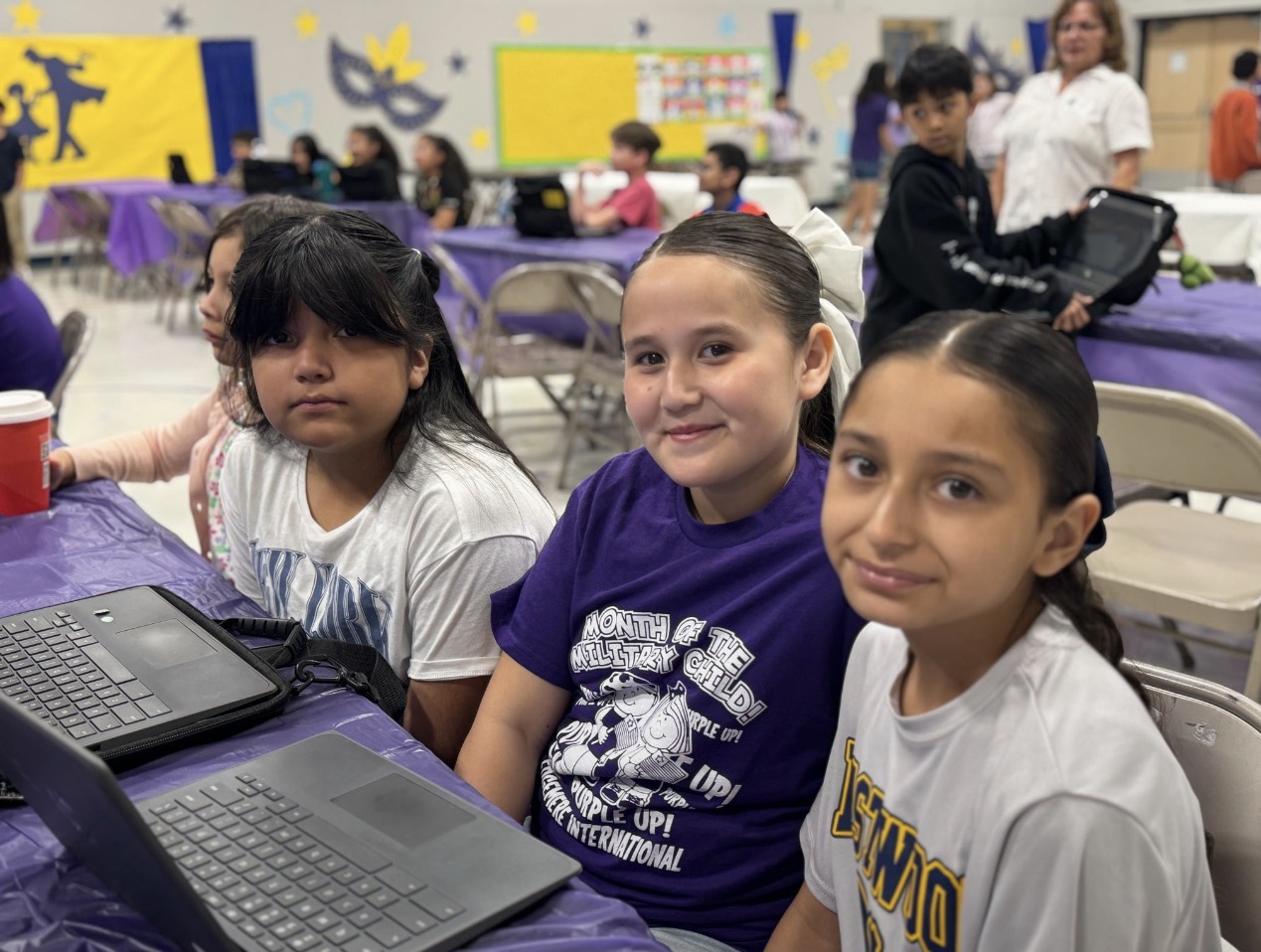 3 students sitting with their laptops in front of them