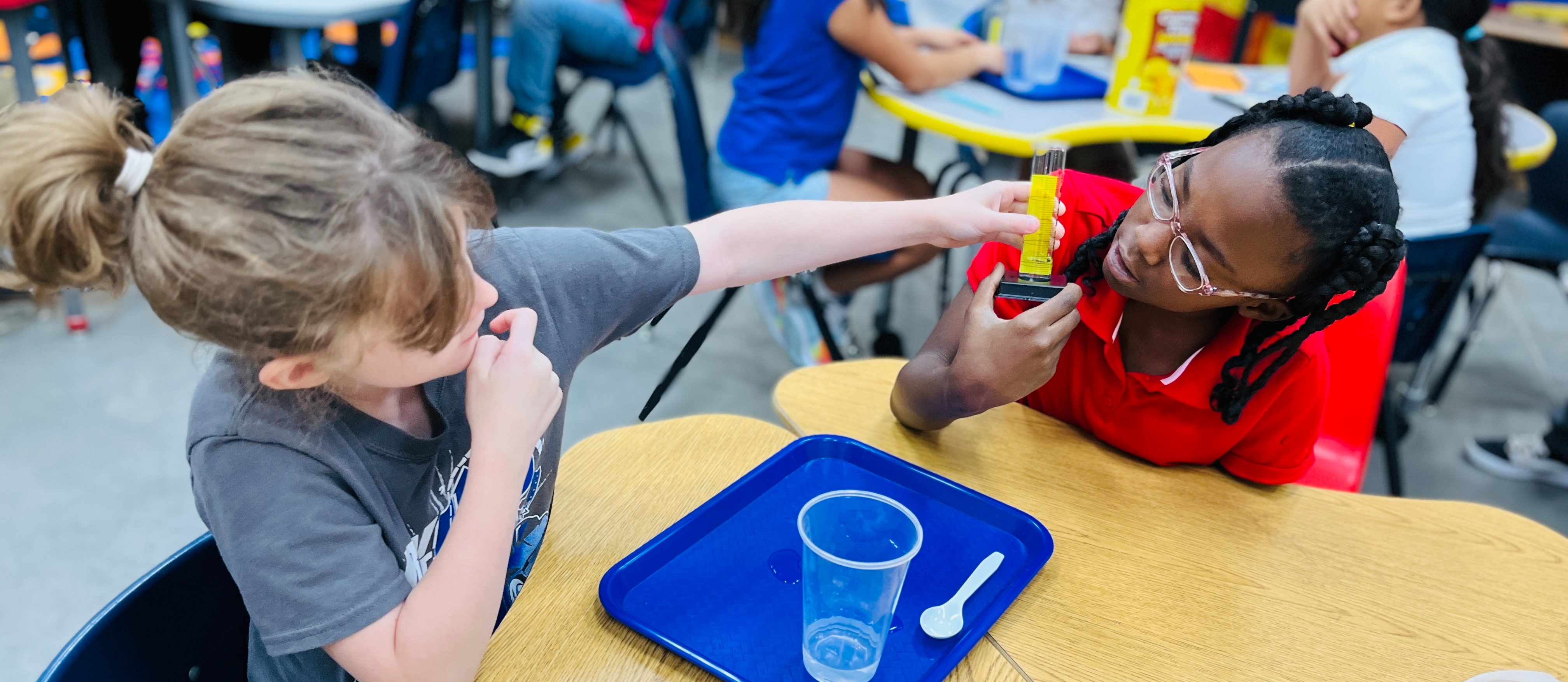 4th grade students measuring water in a graduated cylinder